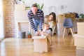 Beautiful famiily, kid playing with his parents riding cardboard fanny box at new home