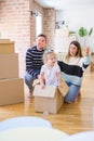 Beautiful famiily, kid playing with his parents riding cardboard fanny box at new home