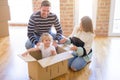 Beautiful famiily, kid playing with his parents riding cardboard fanny box at new home