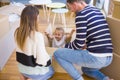 Beautiful famiily, kid playing with his parents riding cardboard fanny box at new home