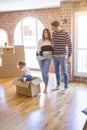 Beautiful famiily, kid playing with his parents riding fanny cardboard box at new home