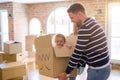 Beautiful famiily, kid playing with his parents riding fanny cardboard box at new home