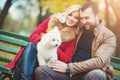 Beautiful family couple with white cute Maltese dog spending time in autumn park. Royalty Free Stock Photo