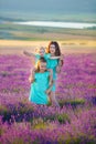 Beautiful family of cute girls enjoy life with girl power on sunset meadow of lavender. Walking mom and daughters in the field of