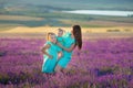 Beautiful family of cute girls enjoy life with girl power on sunset meadow of lavender. Walking mom and daughters in the field of