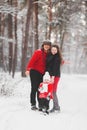 A beautiful family have fun in the winter snowy forest. Mother, father and daugther in red clothes Royalty Free Stock Photo