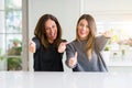 Beautiful family of mother and daughter together at home approving doing positive gesture with hand, thumbs up smiling and happy Royalty Free Stock Photo
