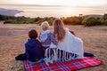 Beautiful family, mother with three children, sitting on blanket and watching sunset over the ocean Royalty Free Stock Photo