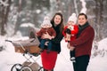 A beautiful family with retro pram walks through the winter snowy forest