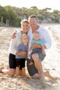 Beautiful family wife and husband holding little daughter and baby boy on beach