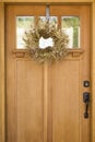 Beautiful, fancy, elegant gold Christmas wreath hanging on wooden front door. Holiday home decorations.