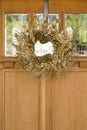 Beautiful, fancy, elegant gold Christmas wreath hanging on wooden front door. Holiday home decorations. Royalty Free Stock Photo