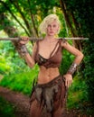 Beautiful fantasy barbarian woman standing on a woodland path holding a spear. 3D rendering