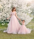 Beautiful fantasy woman gently holds hand little cheerful smiling girl. Happy family mom and daughter walk in blooming Royalty Free Stock Photo