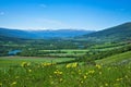 Beautiful farm valley landscape with a flowing river and snow capped mountains Royalty Free Stock Photo