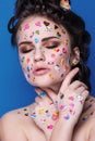 Beautiful fashion girl with luxury professional makeup and funny emoji stickers glued on the face.