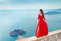 Beautiful Fashion Girl model in gorgeous red dress over the sea, blue sky. Sveti Stefan, Montenegro. Freedom concept. Travel. Vac Royalty Free Stock Photo