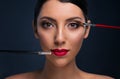 Beautiful fashion model with bright makeup and two cosmetic brushes. Young woman with colored smoky eyes and mat red lips make-up Royalty Free Stock Photo