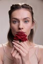 Beautiful fashion model holding red flower near lips portrait Royalty Free Stock Photo