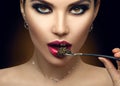 Beautiful Fashion Model woman eating black caviar. Beauty girl portrait with caviar on her lips. Female with spoon of black Caviar