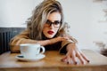 Beautiful fashionable stylish girl sits in a cafe with a cup of coffee. Royalty Free Stock Photo