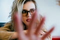 Beautiful fashion stylish girl sits in a cafe in glasses and closes the camera with her hand. Royalty Free Stock Photo