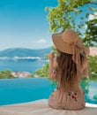 Beautiful Fashion Woman in beach hat enjoying sea view by swimming pool on luxury tropical resort. Exotic Paradise. Royalty Free Stock Photo