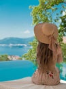 Beautiful Fashion Woman in beach hat enjoying sea view by swimming pool on luxury tropical resort. Exotic Paradise. Royalty Free Stock Photo