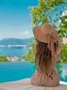 Beautiful Fashion Woman in beach hat enjoying sea view by swimming pool on luxury tropical resort. Exotic Paradise. Royalty Free Stock Photo