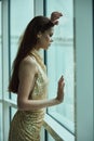 Beautiful fashion woman in stylish expensive gold sequined dress looking out the window at the hotel, Christmas party