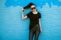 Beautiful fashionable asian girl wearing sunglasses and black clothes outfit posing in front of blue wall. Royalty Free Stock Photo