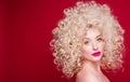 Beautiful fashionable blonde girl in retro style with voluminous curly hairstyle, open shoulders on a red background looks at the Royalty Free Stock Photo