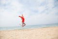 Beautiful fashionable blonde woman on the beach by the sea jumps joyfully Royalty Free Stock Photo