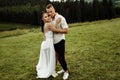 Beautiful fashionable couple at the park. Gorgeous woman in stylish white dress hugging handsome man , enjoy tenderness Royalty Free Stock Photo