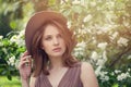 Beautiful fashionable girl in fedora hat in spring flowers garden Royalty Free Stock Photo