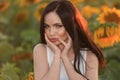 A beautiful fashionable girl with red hair stands in a rapeseed field in a dress, against a background of yellow flowers Royalty Free Stock Photo