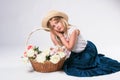 Beautiful fashionable little girl with blond hair with a basket of flowers and a straw hat kanotier Royalty Free Stock Photo