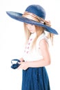 Beautiful fashionable little girl with blond hair in a hat with wide brim and a long fashionable skirt in the studio Royalty Free Stock Photo