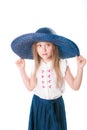 Beautiful fashionable little girl with blond hair in a hat with wide brim and a long fashionable skirt in the studio Royalty Free Stock Photo