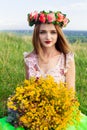 Beautiful fashionable pretty gorgeous girl in dress on the flowers field. Nice girl with wreath of flowers on her head and bouquet Royalty Free Stock Photo