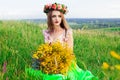 Beautiful fashionable pretty gorgeous girl in dress on the flowers field. Nice girl with wreath of flowers on her head and bouquet Royalty Free Stock Photo