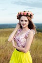 Beautiful fashionable pretty gorgeous girl in dress on the flowers field. Nice girl with wreath of flowers on her head and bouquet Royalty Free Stock Photo
