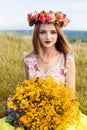 Beautiful fashionable pretty gorgeous girl in dress on the flowers field. Nice girl with wreath of flowers on her head and bouquet Royalty Free Stock Photo