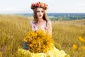 Beautiful fashionable pretty gorgeous girl in dress on the flowers field. Nice girl with wreath of flowers on her head and bouquet Royalty Free Stock Photo