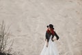 Beautiful and fashionable red-haired model girl in the leather jacket, in the black hat and in stylish wedding dress Royalty Free Stock Photo