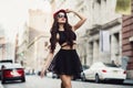 Beautiful fashionable sexy woman walking on city street wearing a black skirt, hat and sunglasses. Royalty Free Stock Photo