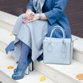 Beautiful fashionable shoes on women`s leg. Stylish ladies accessories. blue shoes and bag, coat with dress or skirt. Royalty Free Stock Photo