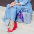 Beautiful and fashionable shoes on women`s leg. woman. Stylish ladies accessories. red shoes, blue bag, denim dress or skirt. Royalty Free Stock Photo