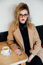 Beautiful fashionable stylish girl sits in a cafe with a cup of coffee.