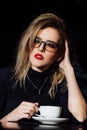 Beautiful fashionable stylish girl sits in a cafe with a cup of coffee. Royalty Free Stock Photo